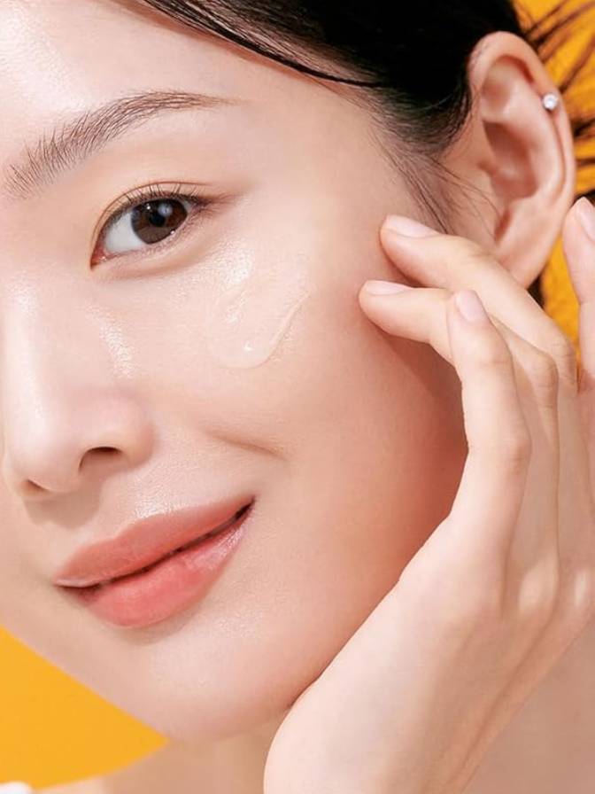 Close-up of a person's face with a hand touching their cheek, against a yellow background