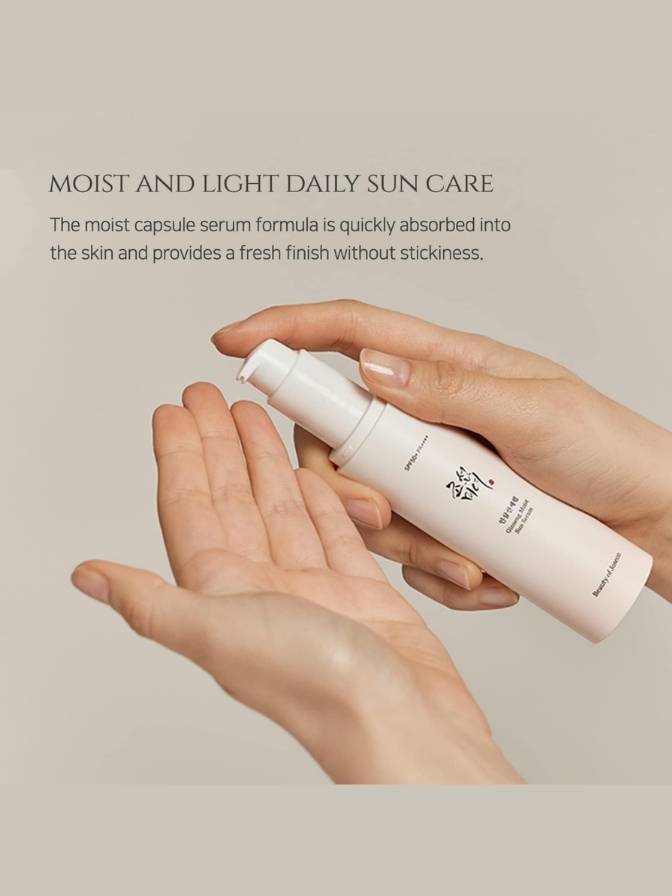 Hand holding a white bottle of moisturizing serum with text about daily sun care on a beige background