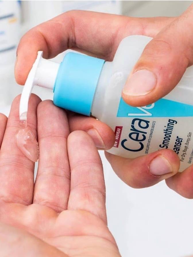 Person holding a bottle of CeraVe Smoothing Cleanser with a white background