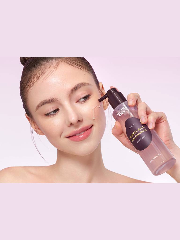 Woman applying a cosmetic product to her face with a pink background