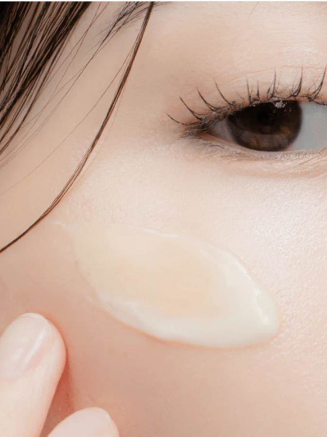Close-up of a person applying cream to their face with a blurred background