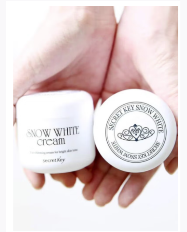 Hand holding two containers of Secret Key Snow White cream.