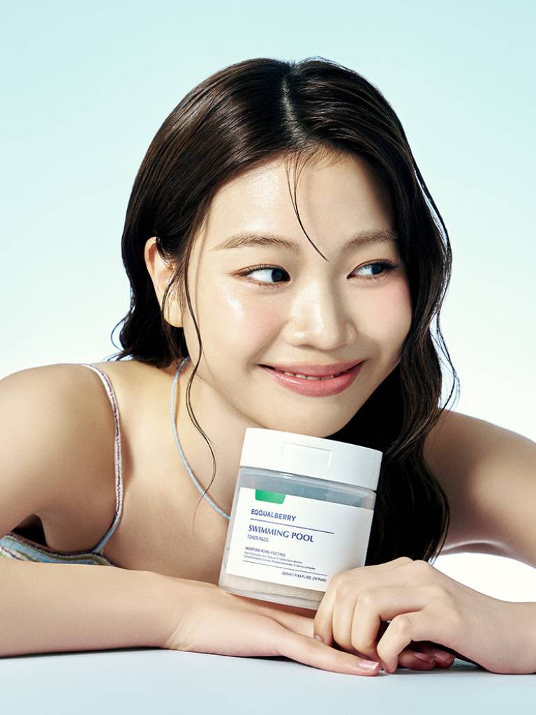 Woman holding a skincare product with a light blue background
