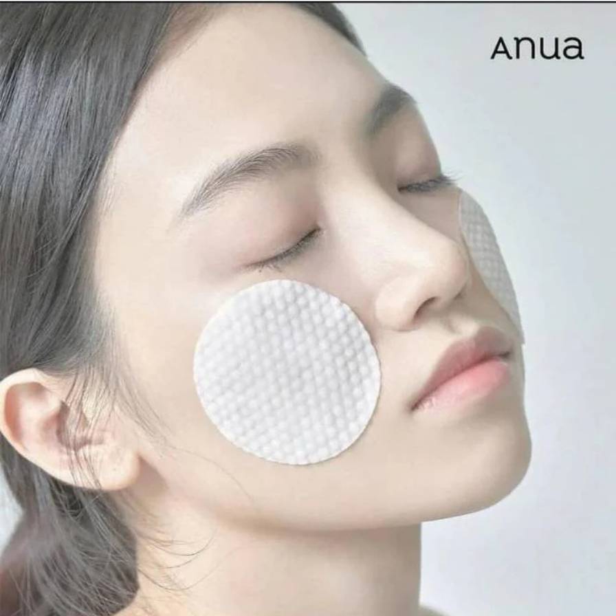 Woman wearing white patches on her face with 'Anua' branding.