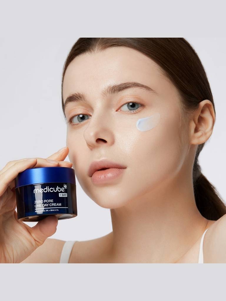 Woman holding a jar of Medicube cream with a white background