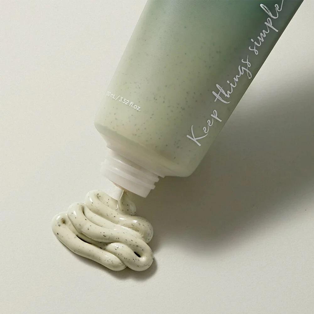 Bottle of cream with a white pump dispensing cream onto a light gray background