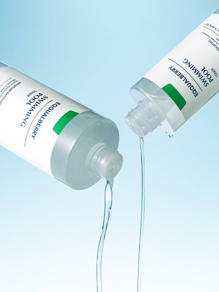 Two bottles of Ecolab skincare products with liquid being poured from one onto a blue background