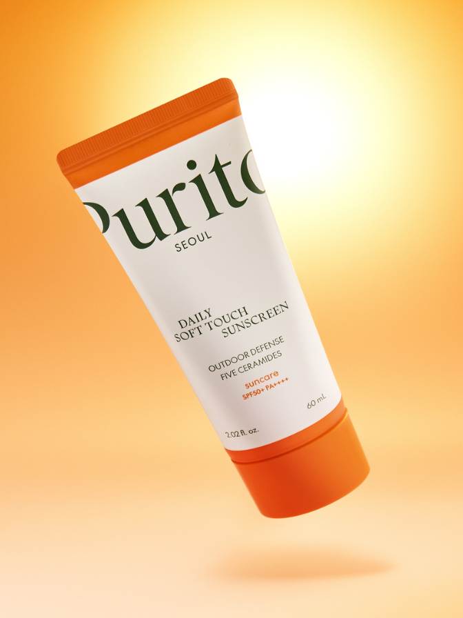 Purito sunscreen tube on a gradient orange background