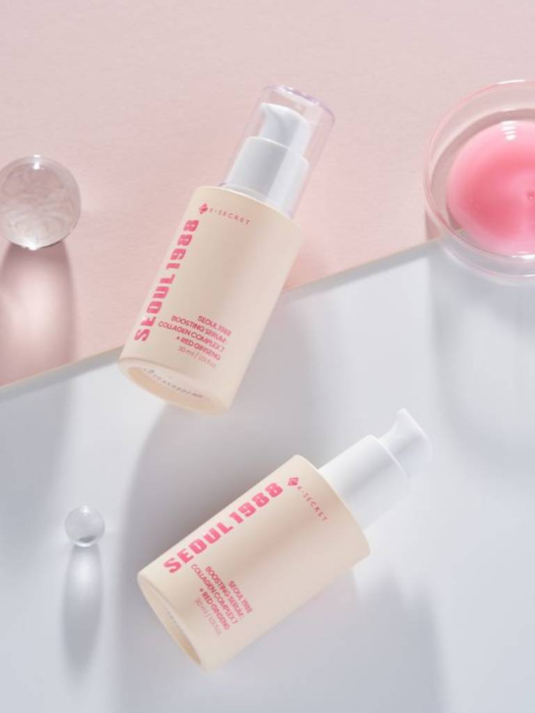 Two skincare bottles with visible text on a light pink background