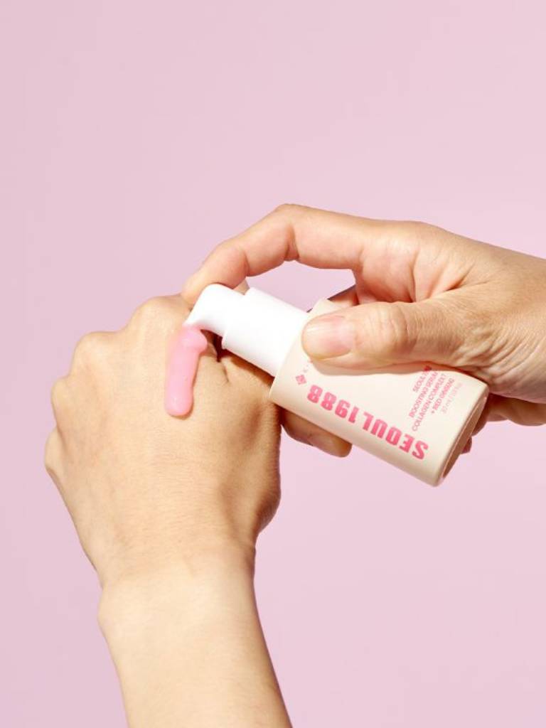 Hand holding a pink skincare product with 'Seoul 1988' branding against a light pink background