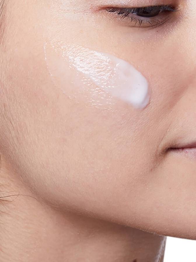 Close-up of a woman applying cream to her face