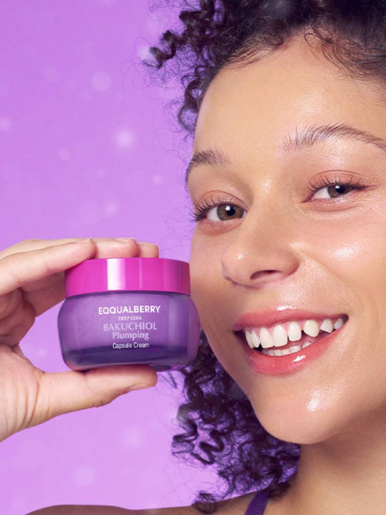 Person holding a purple skincare product with a purple background