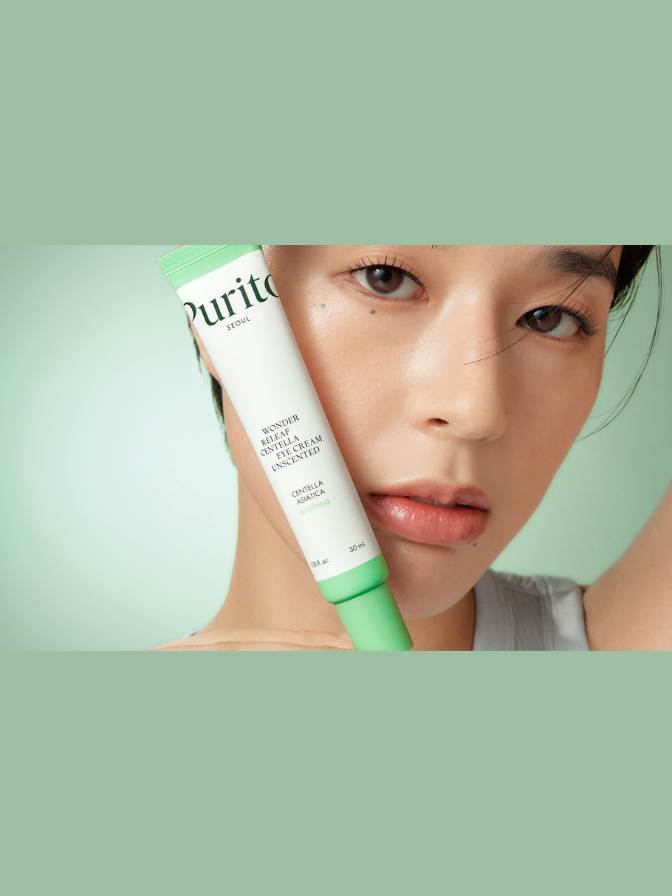 Woman holding a Purito skincare product against a green background