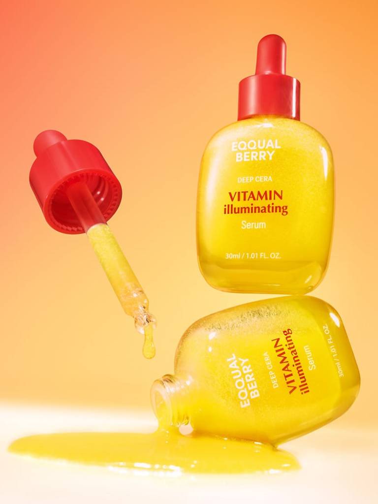 Yellow skincare serum bottle with red cap on a gradient orange background