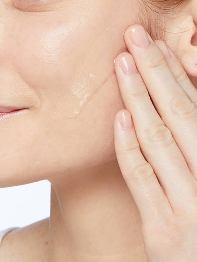 Close-up of a person's face with a hand gently touching the skin.