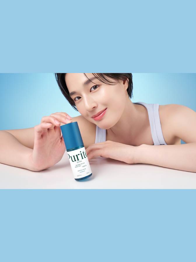Woman holding a bottle of 'uritu' skincare product against a light blue background