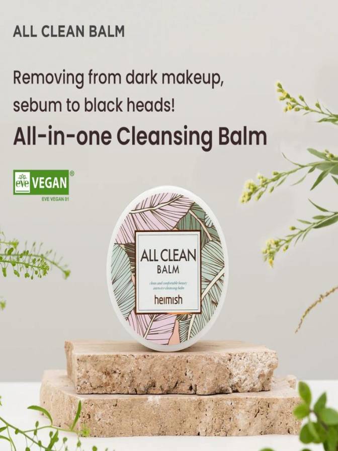 Heimish All Clean Balm on a natural stone surface with greenery, promoting its use for dark makeup removal and sebum control.