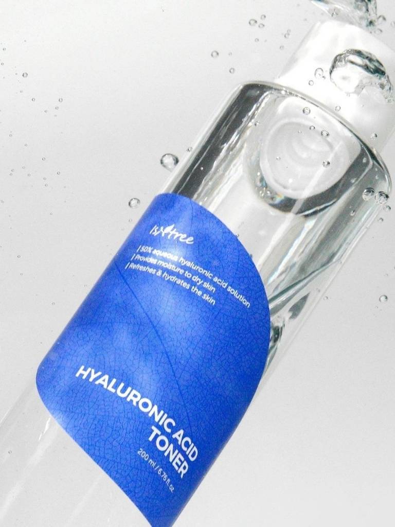 Clear bottle of hyaluronic acid toner with a blue label on a light gray background