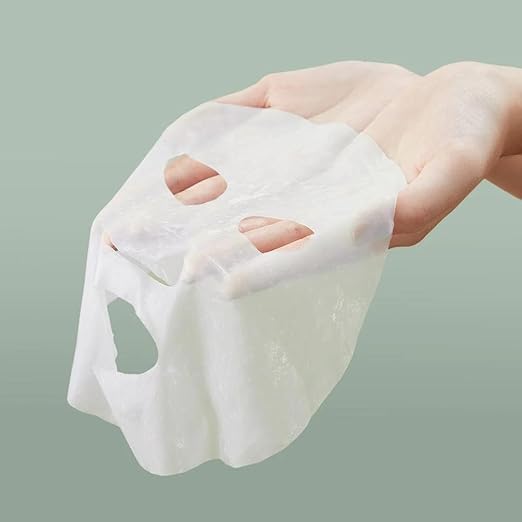White cube-shaped mask held by a hand against a light green background