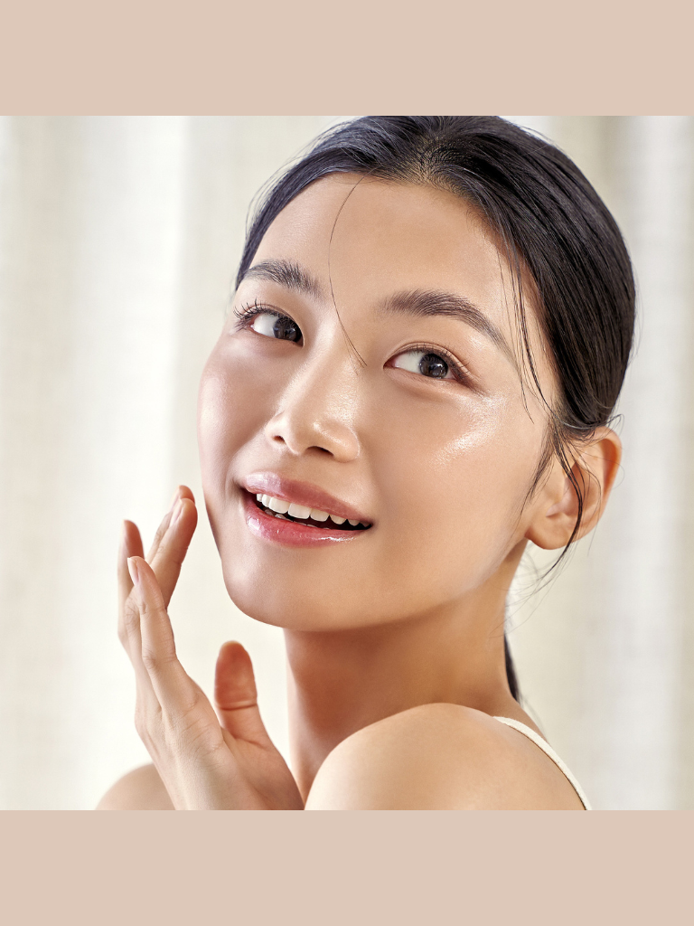Woman applying cream to her face with a soft, neutral background