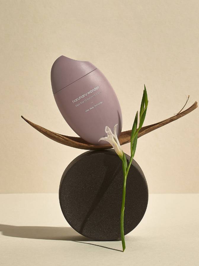 Cosmetic bottle with a leaf on a beige background