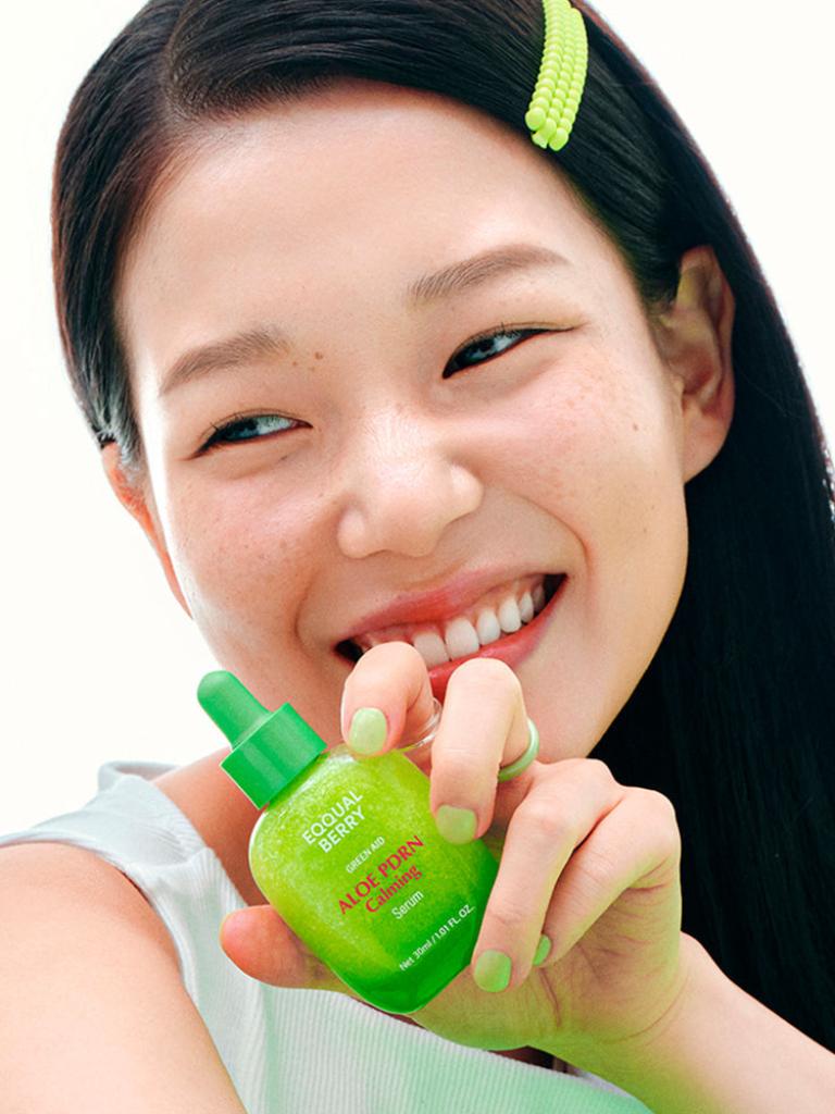 Woman holding a green bottle of aloe vera gel brand name "Eqqualberry"with a white background