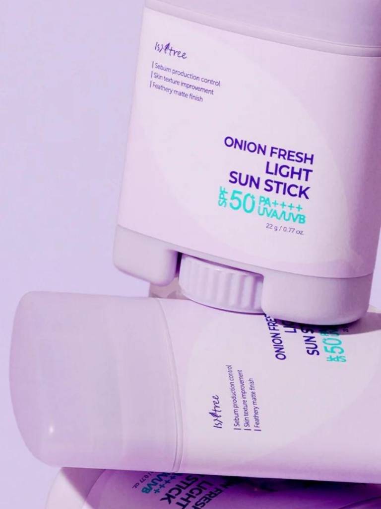 Onion Fresh Light Sun Stick with purple and white packaging on a light purple background