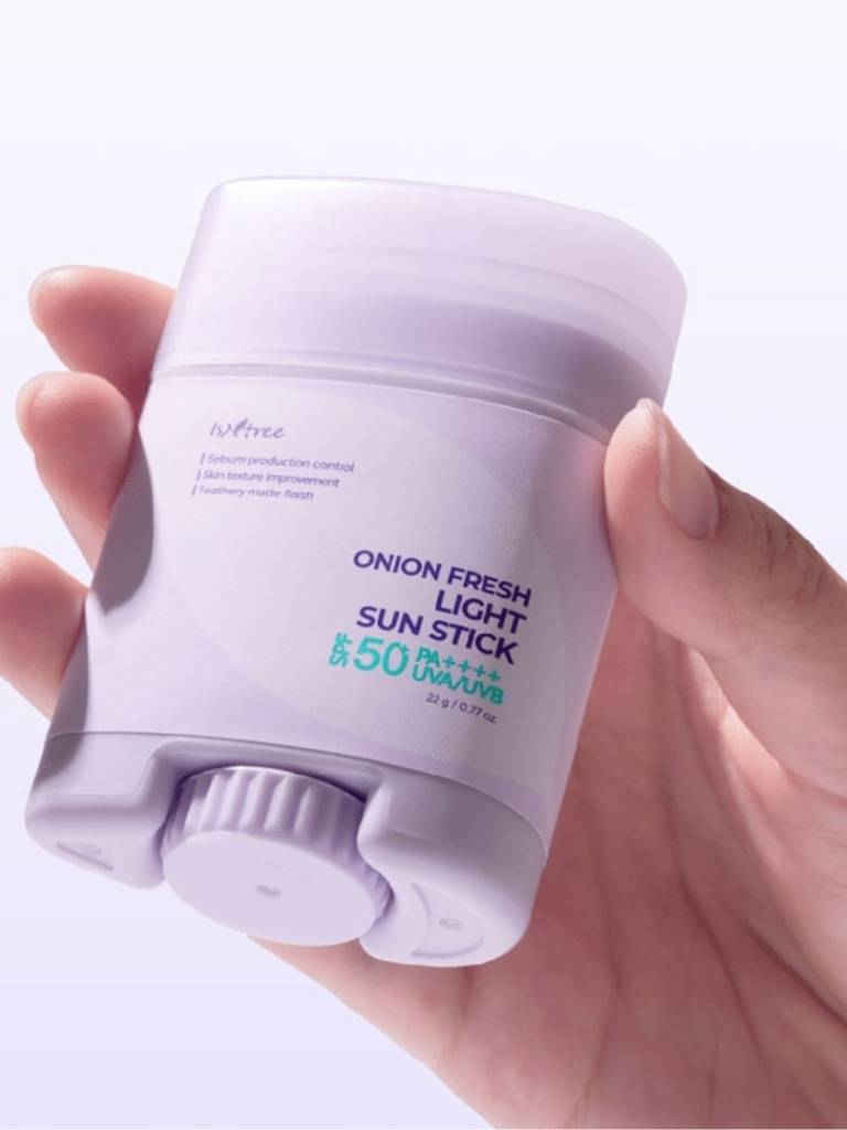 Hand holding a white sun stick with text on a light purple background
