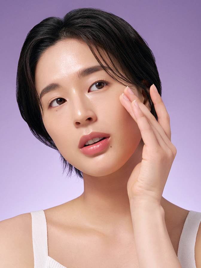 Woman touching her face against a purple background