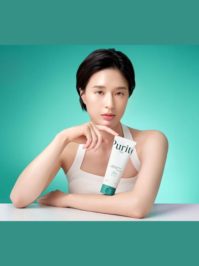 Woman holding a skincare product with 'Purito' branding against a teal background