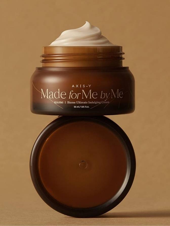 Brown jar of cream with a dollop of white cream on a beige background