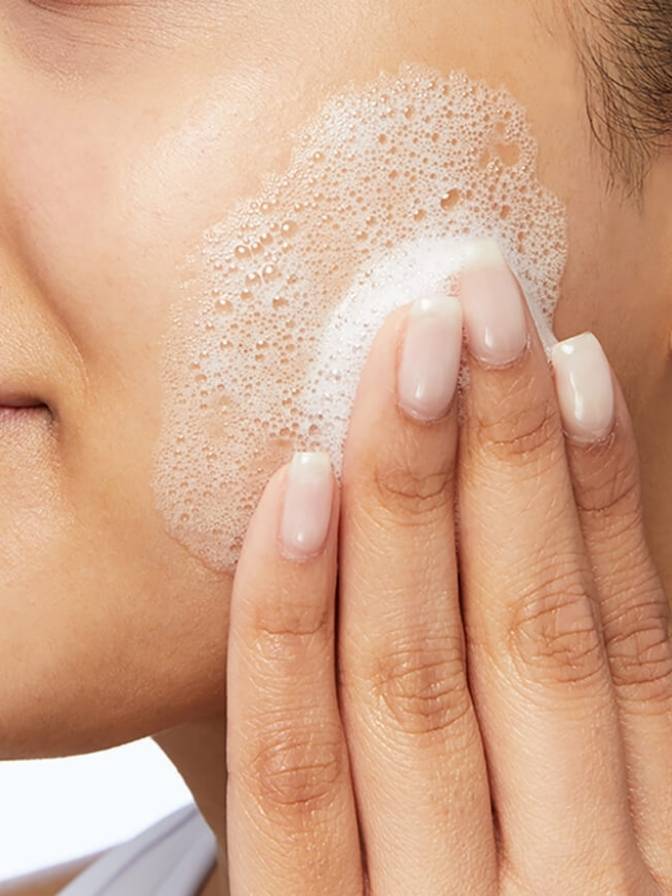 Person applying a skincare product to their face with a sponge applicator.