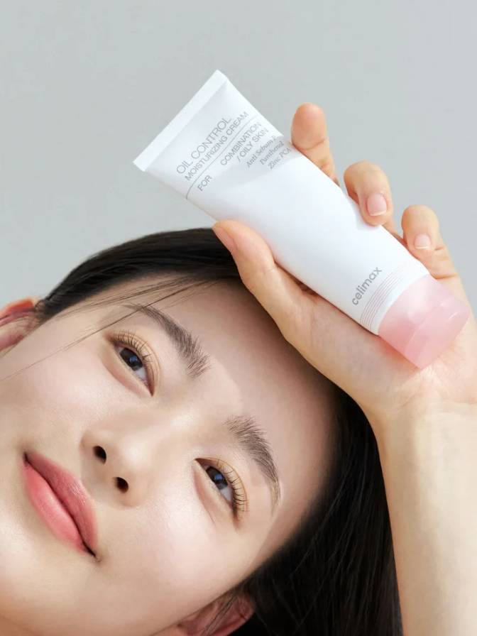 Person holding a skincare product with a neutral background