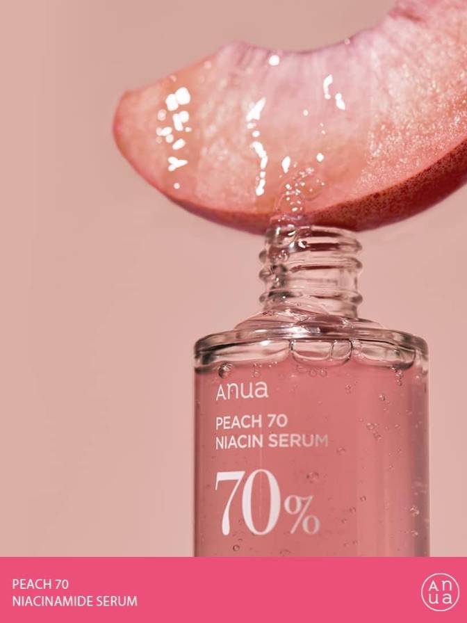 Anua Peach 70 Niacinamide Serum bottle with pink peach half on a pink background