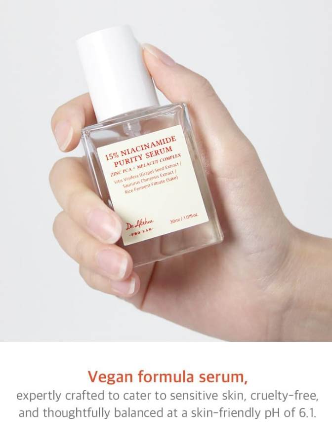 Hand holding a skincare serum bottle with product details on a light gray background