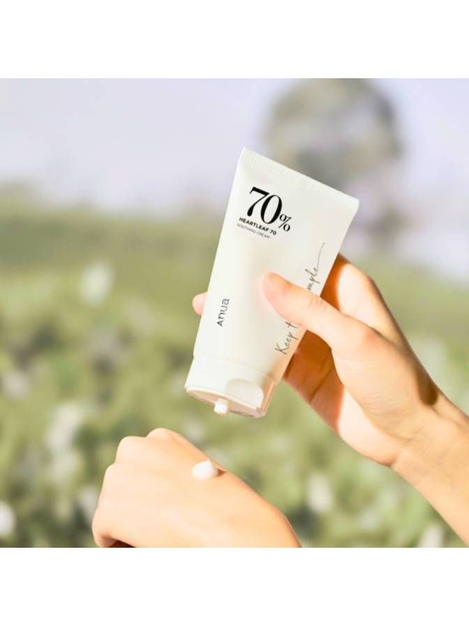 Hand holding a skincare product with a blurred natural background