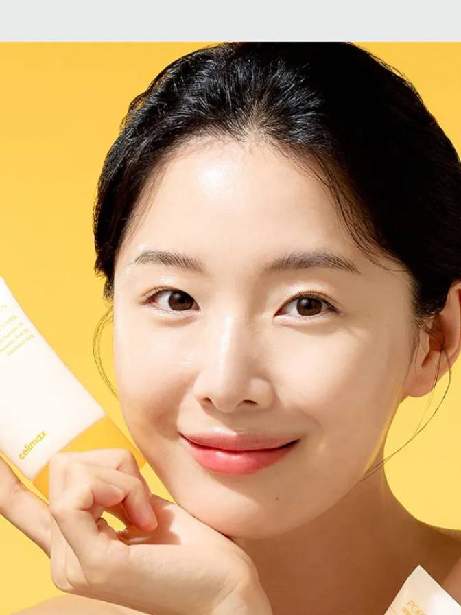 Woman holding a skincare product against a yellow background